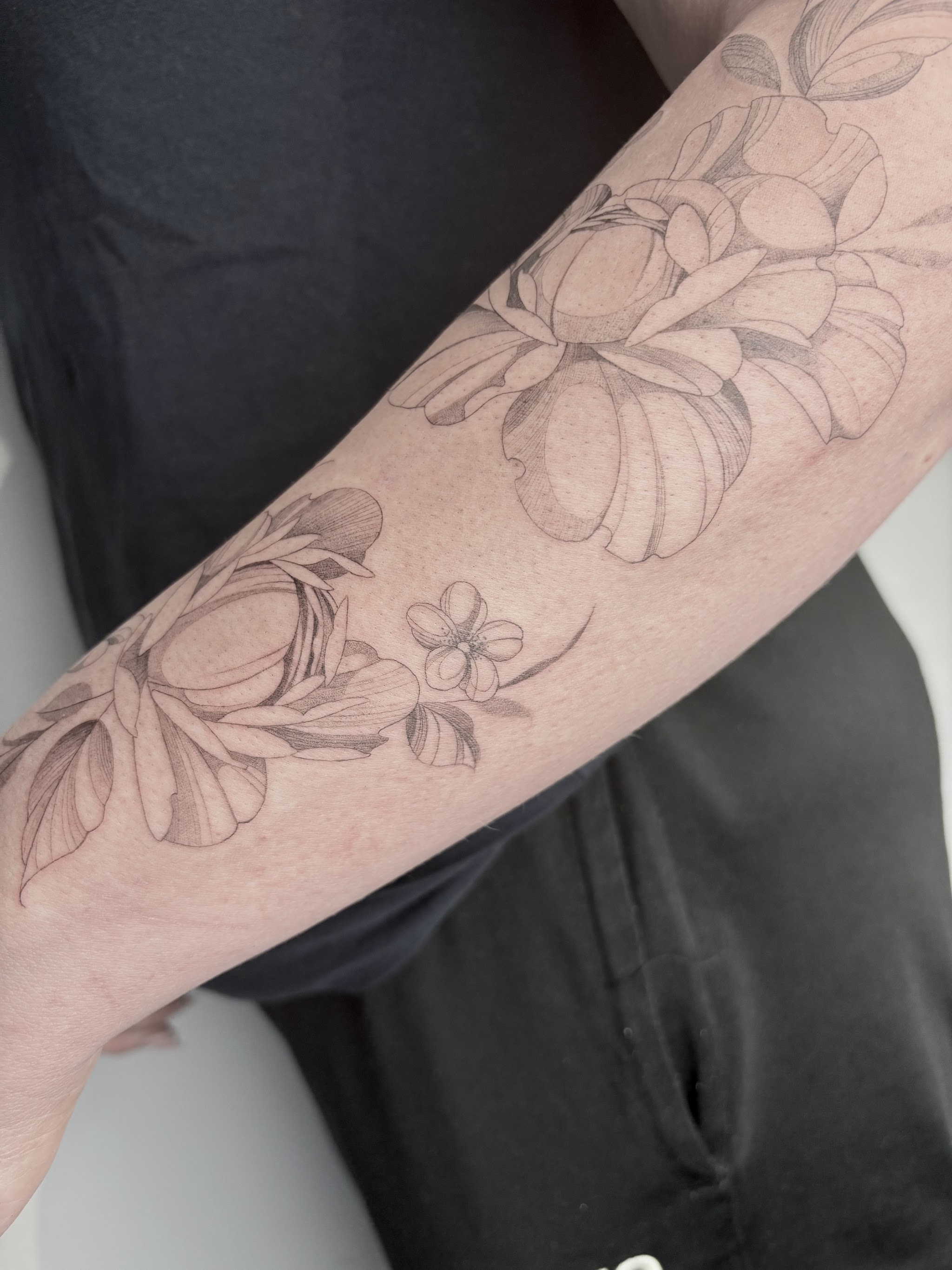 Onderarm met een tattoo van fijne bloemen in fijne lijnen