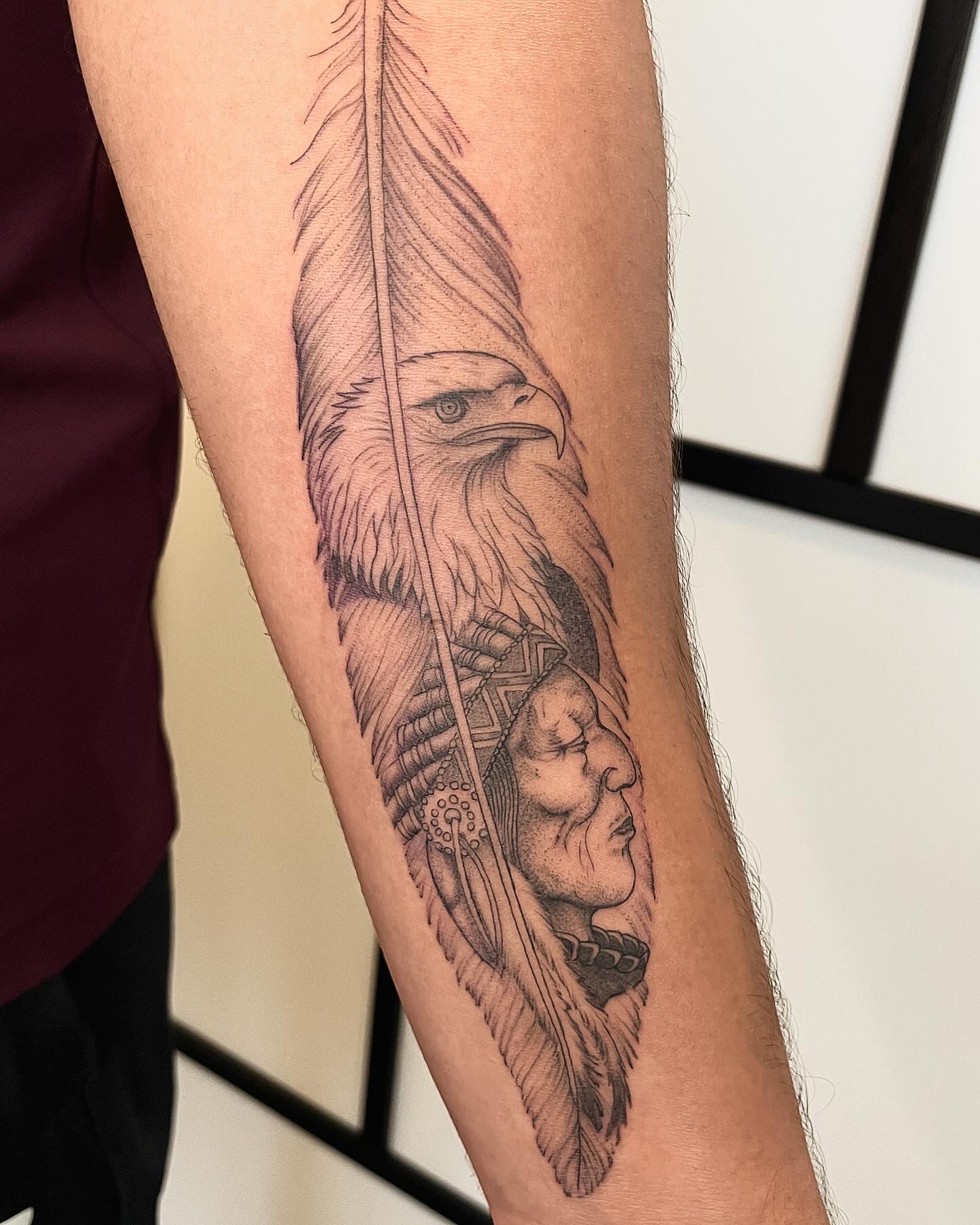 Onderarm met een adelaar, een veer en een portret in zwart en grijs